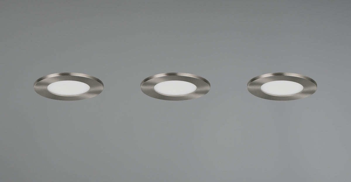 Trois spots encastrés au plafond gris, collerette nickel et diffuseur blanc, alignés.