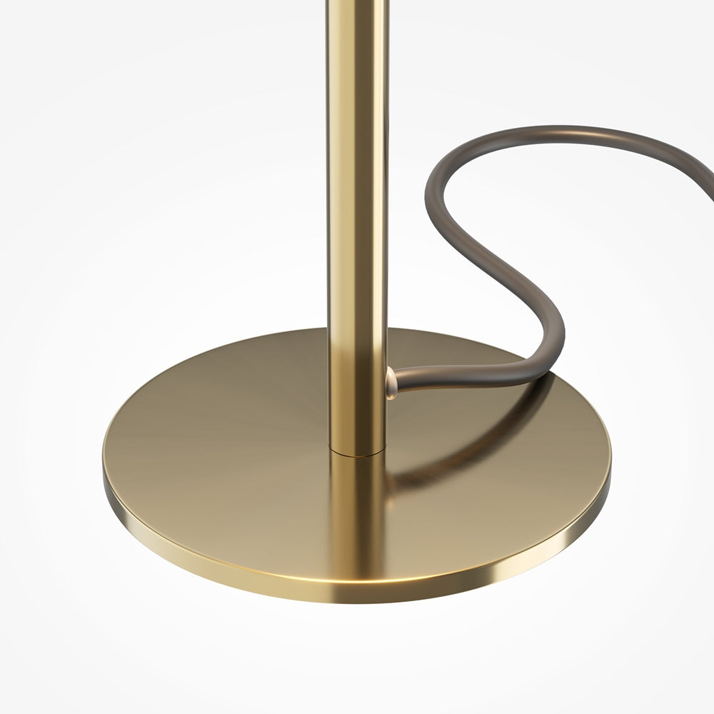 Détail de la base ronde bronze et du câble noir avec interrupteur, pied doré.