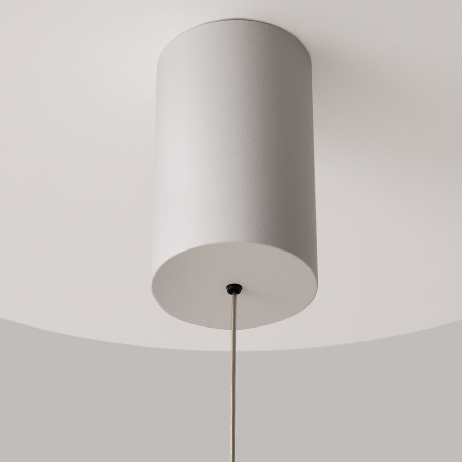 Détail de la rosace cylindrique blanche fixée au plafond et du câble