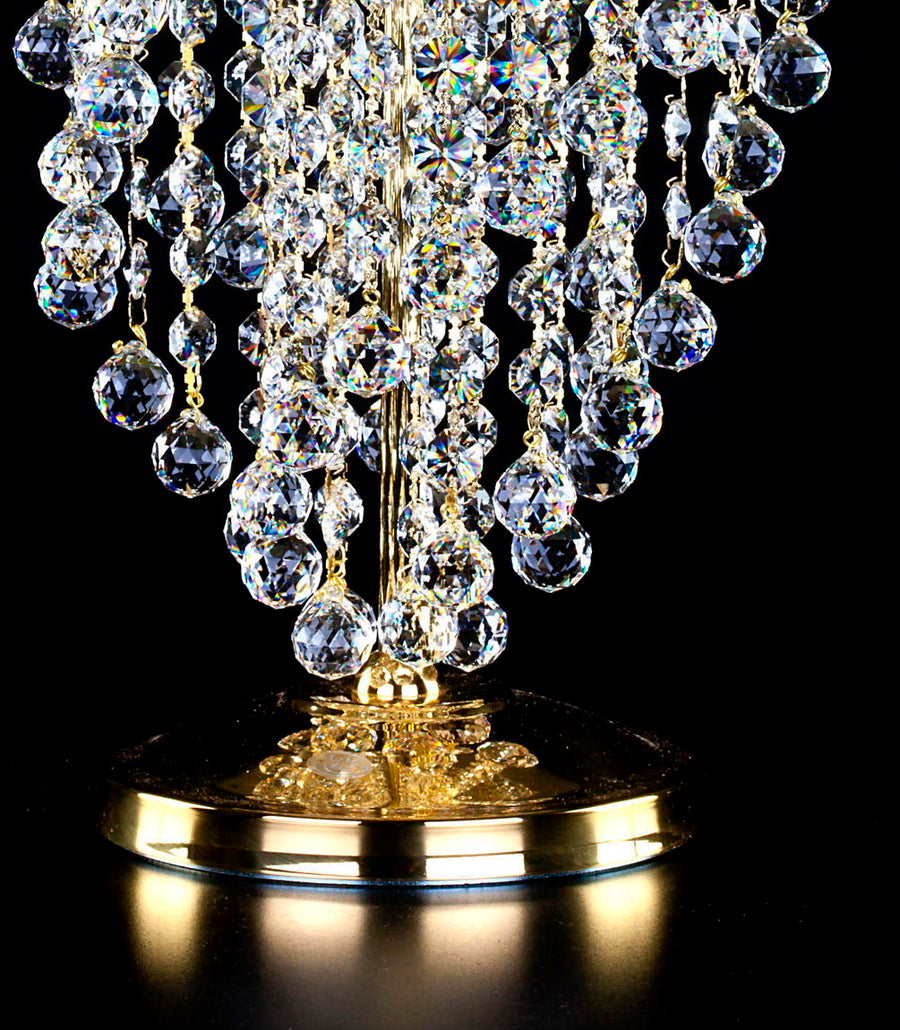 Gros plan du socle doré et des dernières gouttes de cristal suspendues