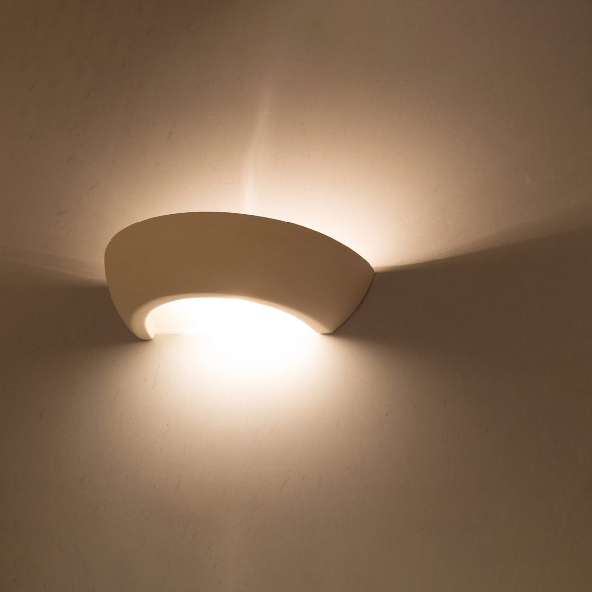 Applique allumée diffusant une lumière chaude sur un mur beige