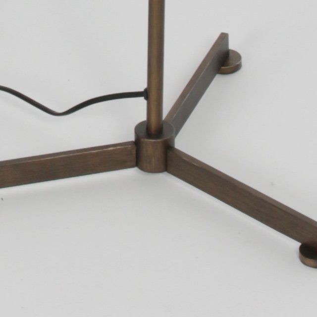 Détail de la base tripode bronze avec câble d'alimentation au sol.