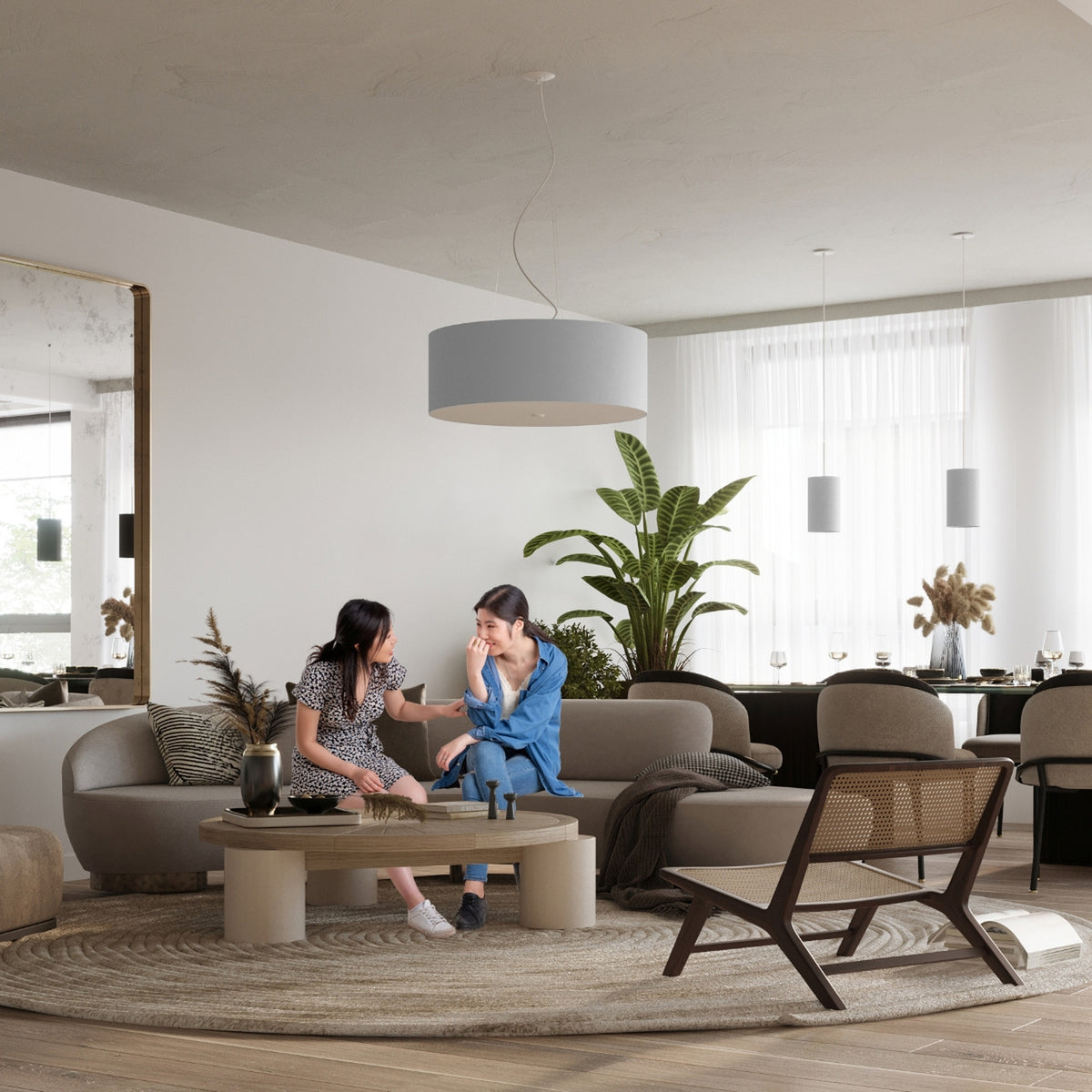 Mise en ambiance dans un salon contemporain, luminaire cylindrique suspendu au-dessus du coin salon.