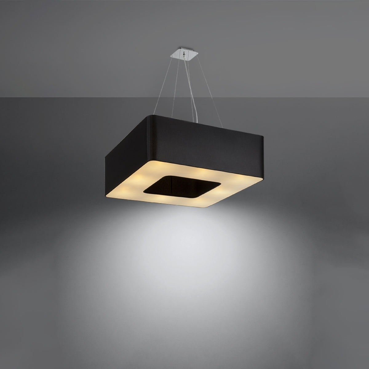 Luminaire suspendu allumé projetant une lumière chaude, diffuseur blanc éclairé, intérieur noir.