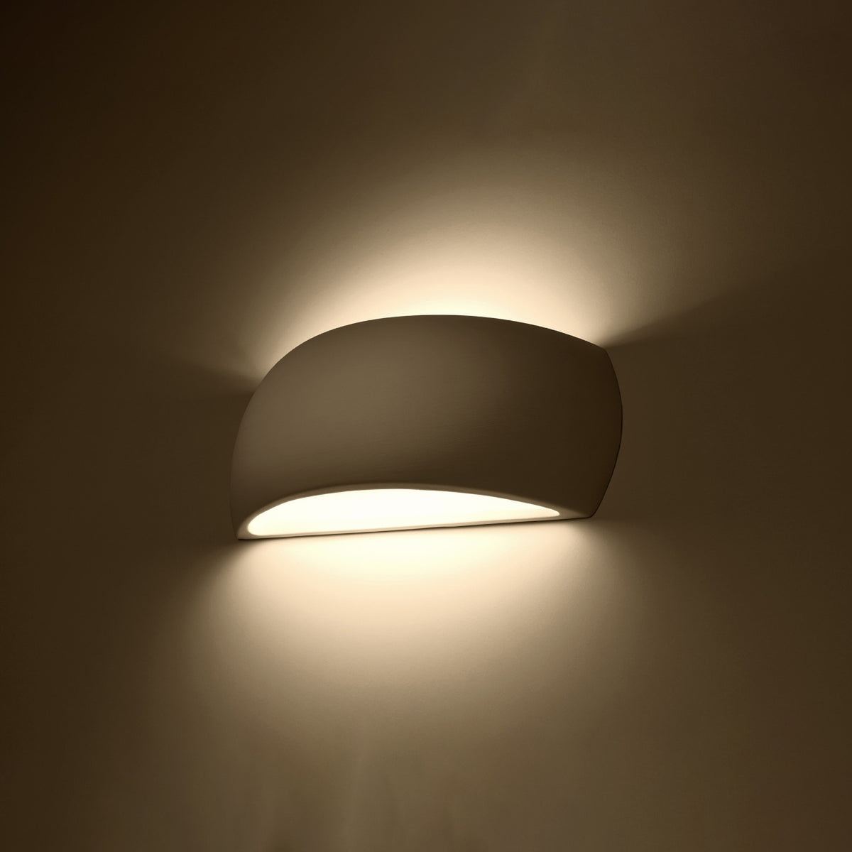 Applique allumée dans une pièce sombre, halo lumineux diffusé en haut et en bas.