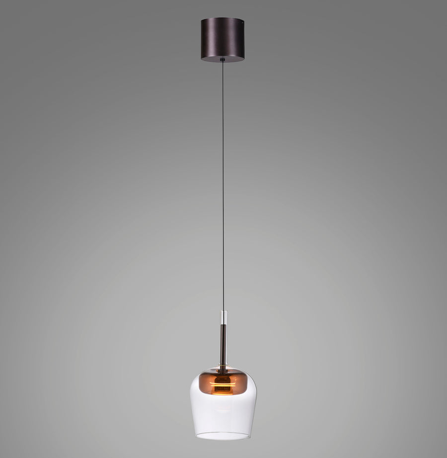 Suspension seule allumée, verre transparent et calotte cuivrée, câble fin sur fond gris.