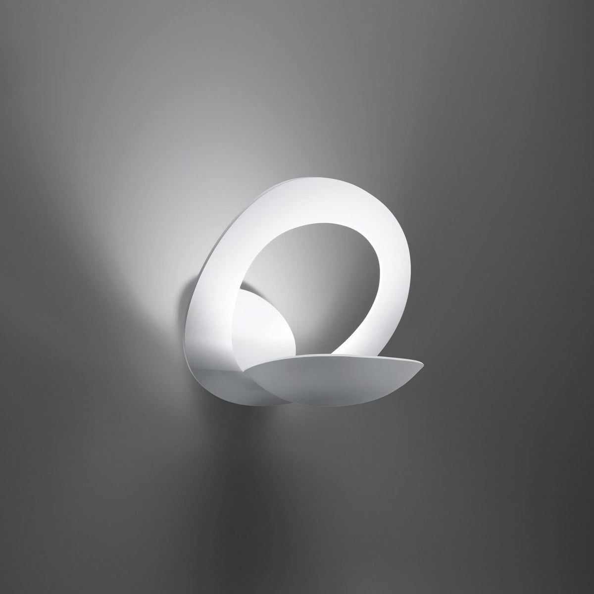 Mise en ambiance sur mur gris, halo lumineux diffusé par l’applique blanche.