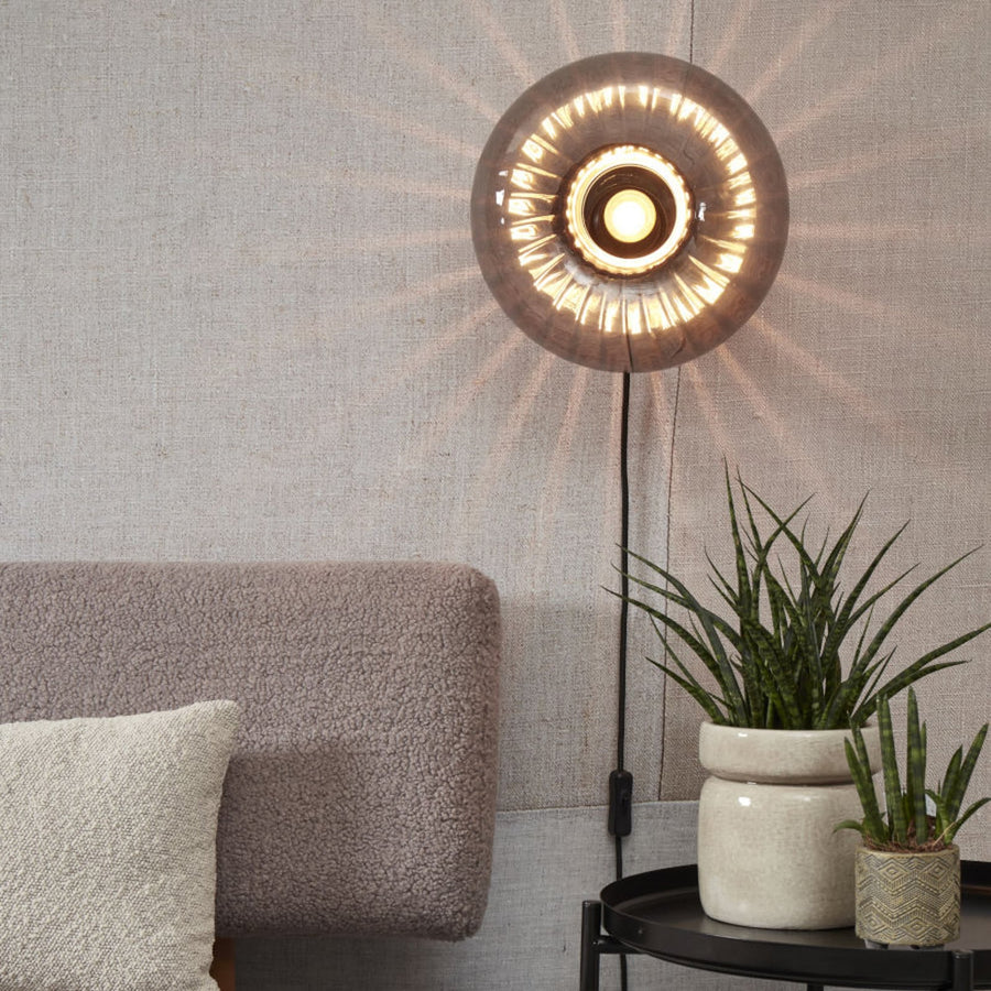 Applique murale allumée fixée au mur au-dessus d’un canapé et d’une plante