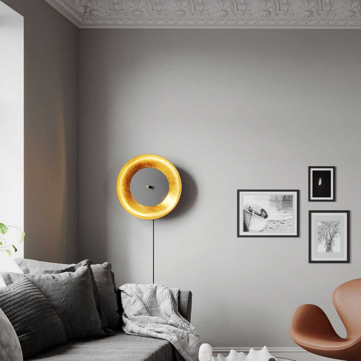 Applique murale dorée et noire installée sur un mur gris au-dessus du canapé