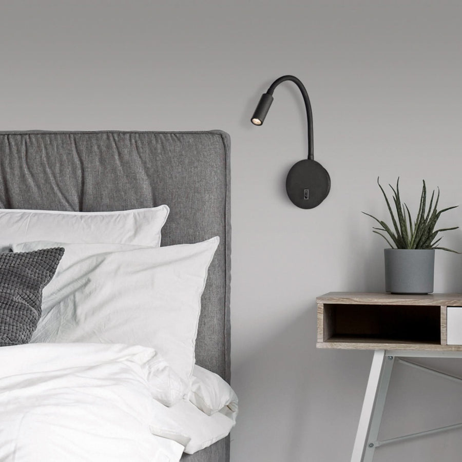 Seconde vue de l'applique noire au-dessus du lit, avec coussins et table de chevet.