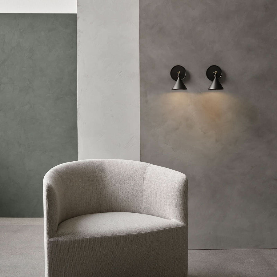 Deux appliques murales allumées au-dessus d'un fauteuil dans un intérieur.