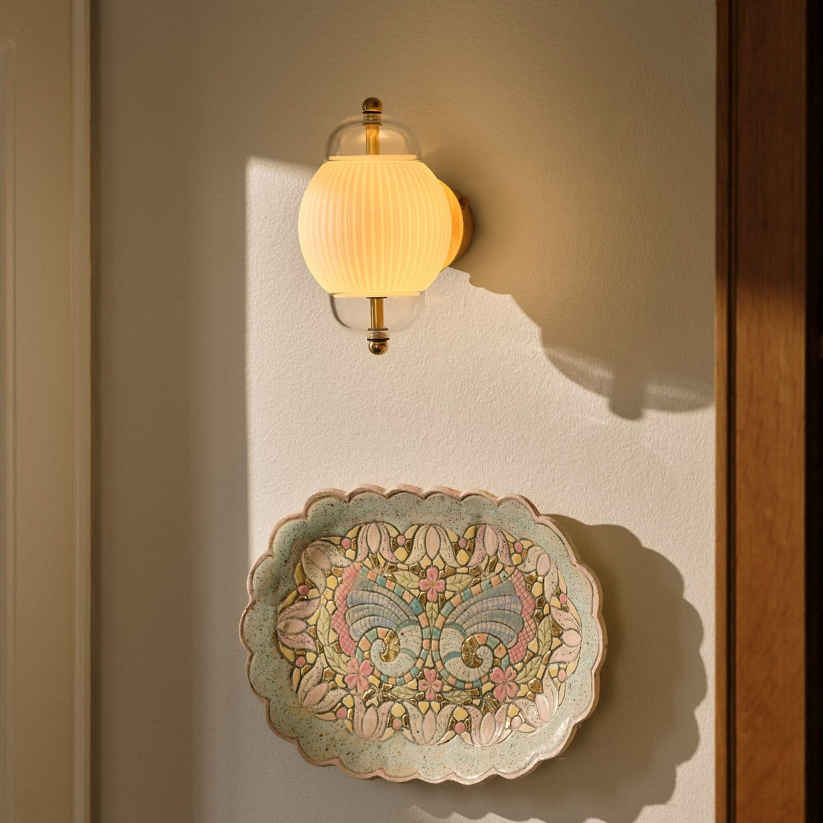 Mise en ambiance : applique allumée au-dessus d'une assiette décorative murale.
