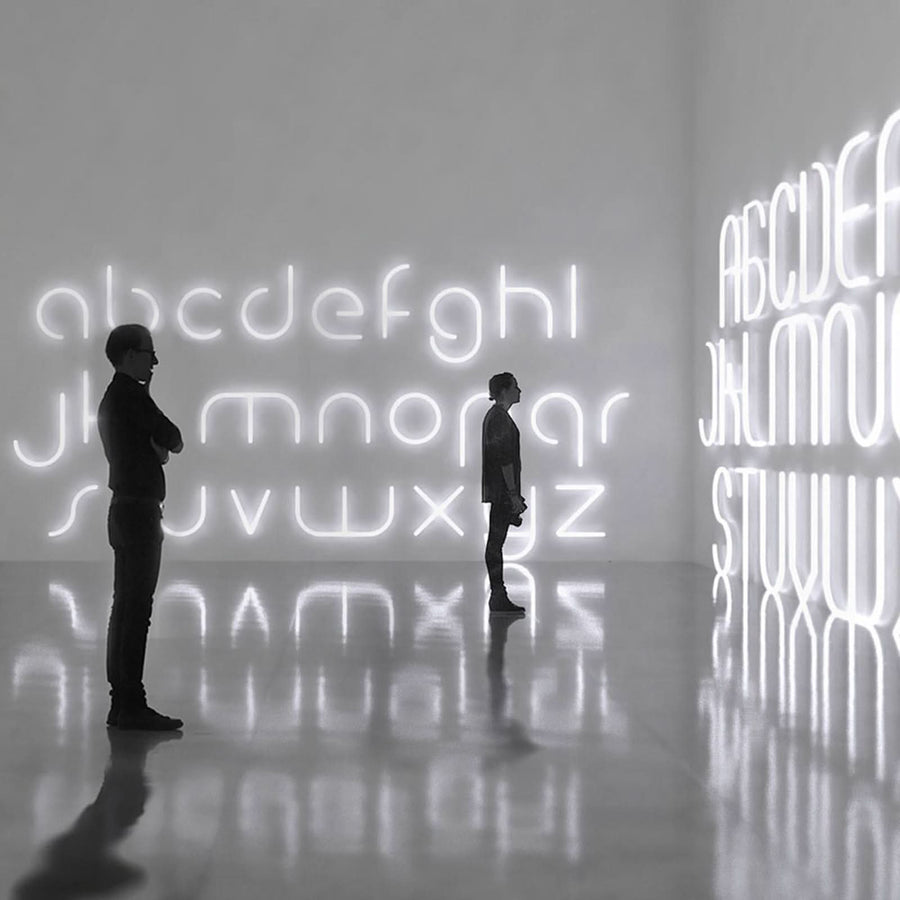 Deux silhouettes contemplent des lettres lumineuses géantes reflétées au sol