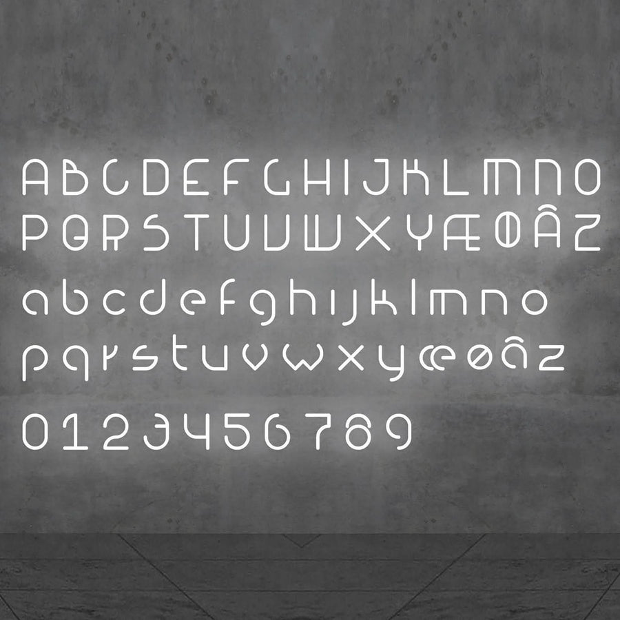 Alphabet complet de lettres et chiffres lumineux blancs alignés sur un mur gris.