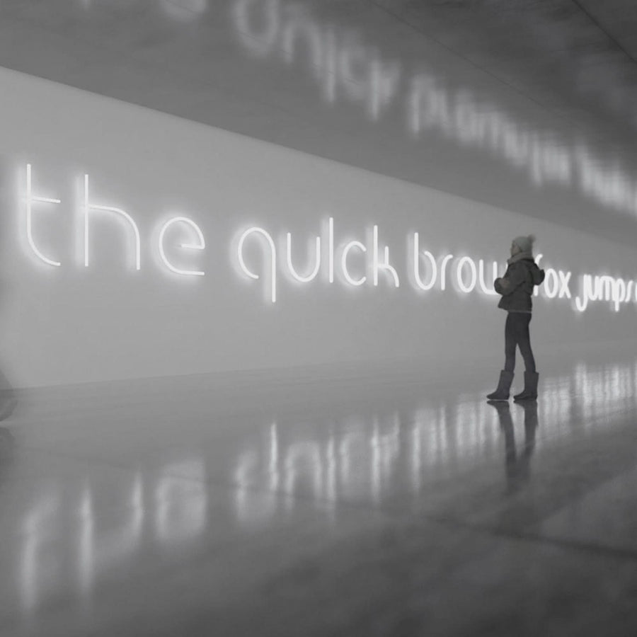 Personne debout devant une phrase lumineuse en néon blanc dans un espace réfléchissant.