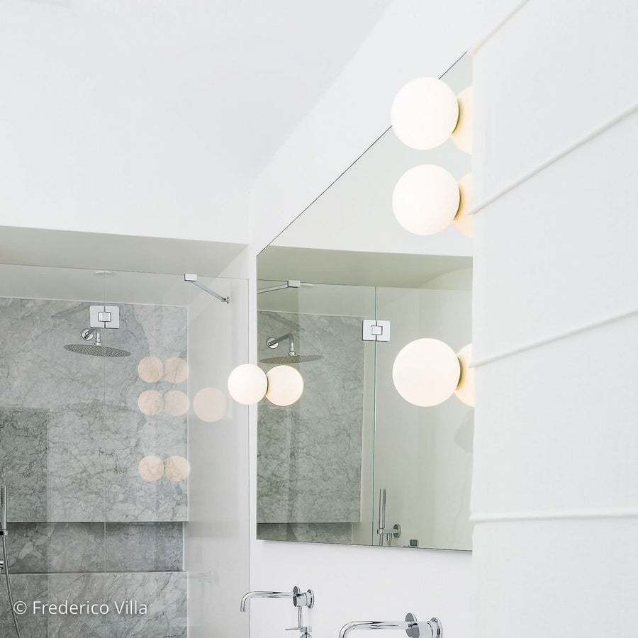 Vue rapprochée de l’applique sphérique blanche fixée près d’un miroir, salle de bain.