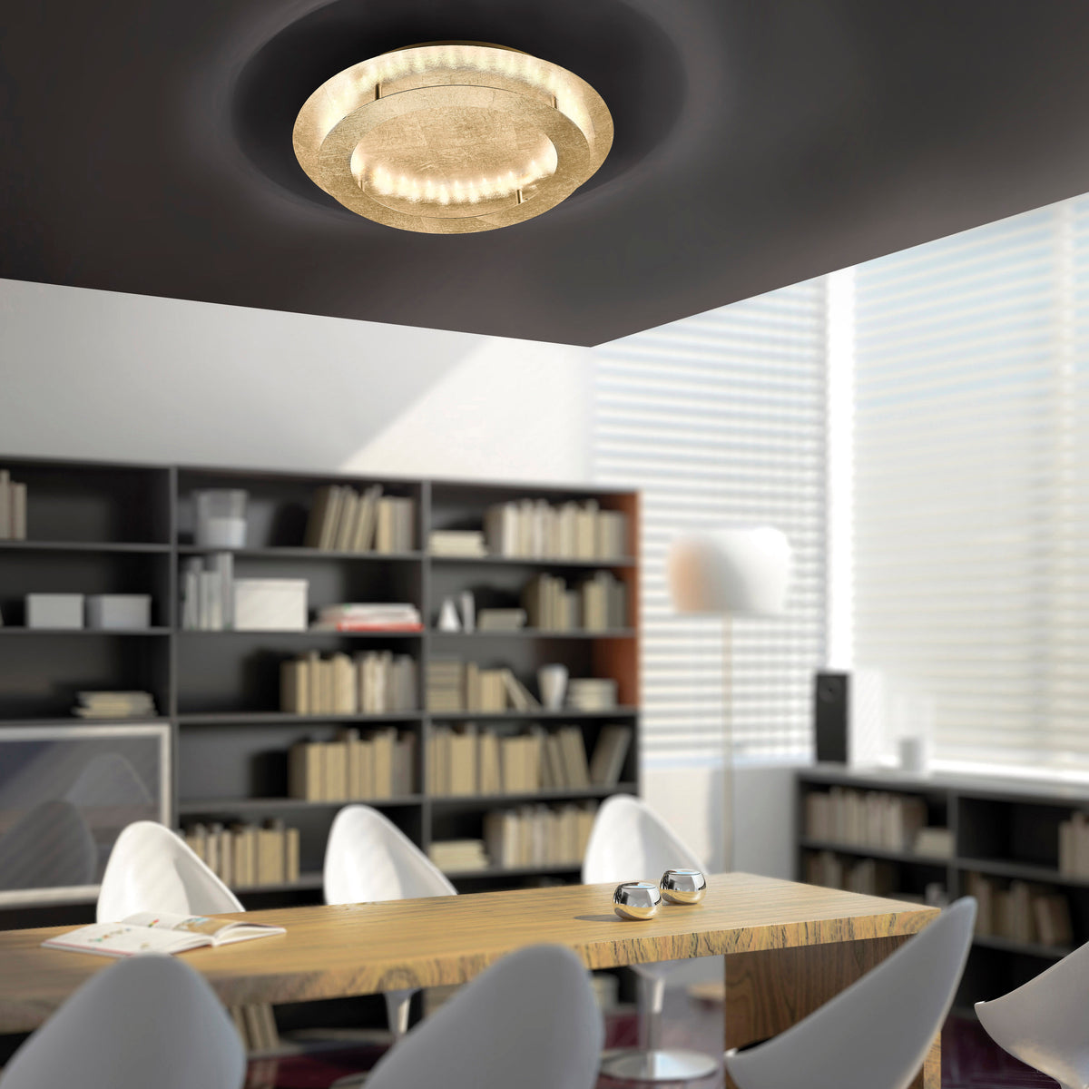 Plafonnier doré circulaire éclairant une salle à manger avec bibliothèque et table en bois