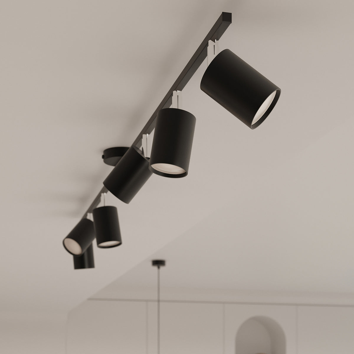 Détail en plongée des cylindres noirs orientables suspendus sous un plafond blanc