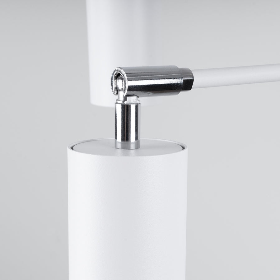 Gros plan sur l'articulation chromée entre le bras blanc et le cylindre orientable du luminaire.