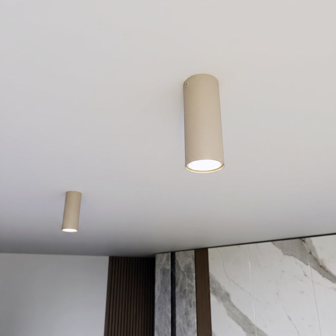 Vue en situation, deux plafonniers cylindriques beige fixés au plafond d'une pièce.