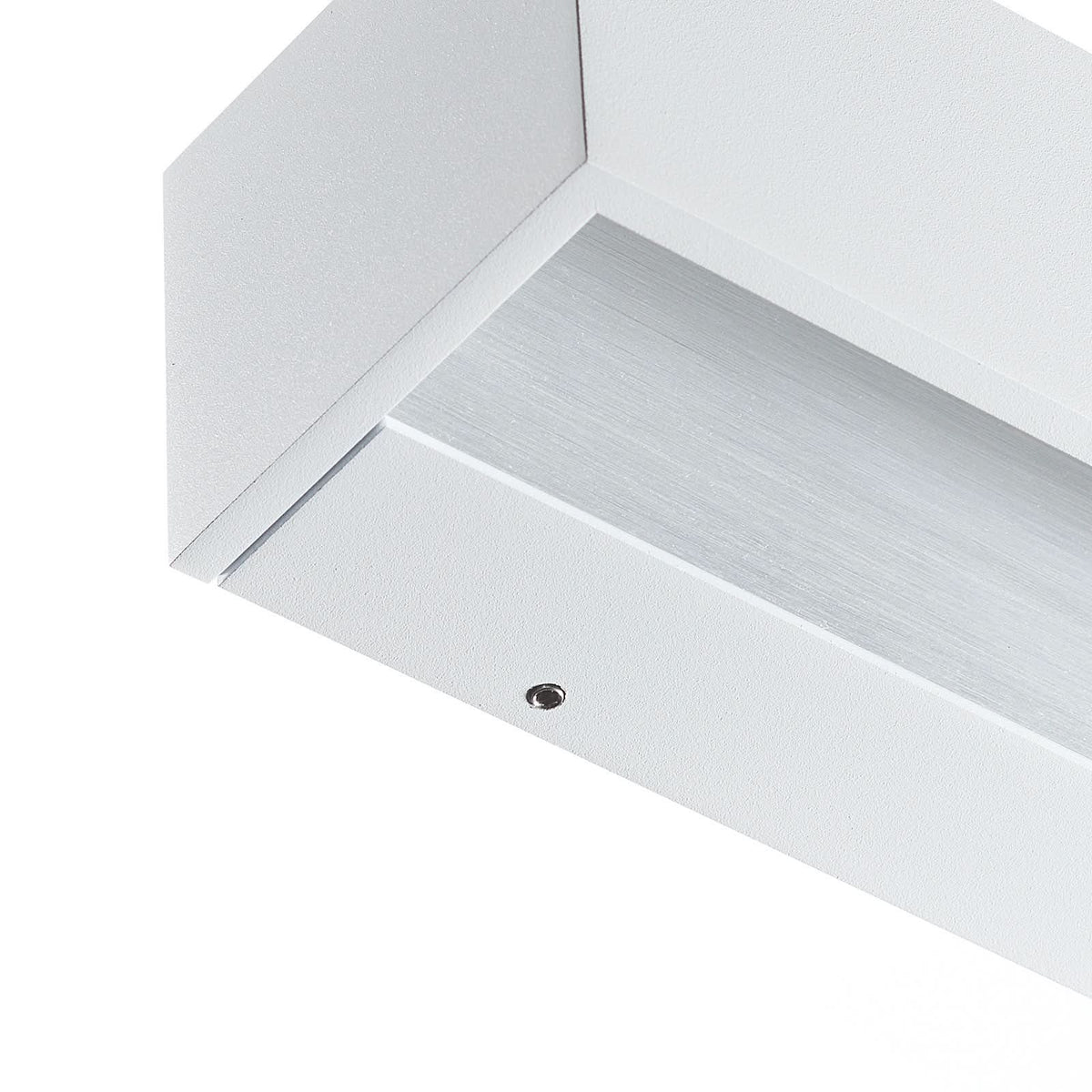 Détail de l'angle en aluminium blanc, vis apparente et diffuseur brossé strié.