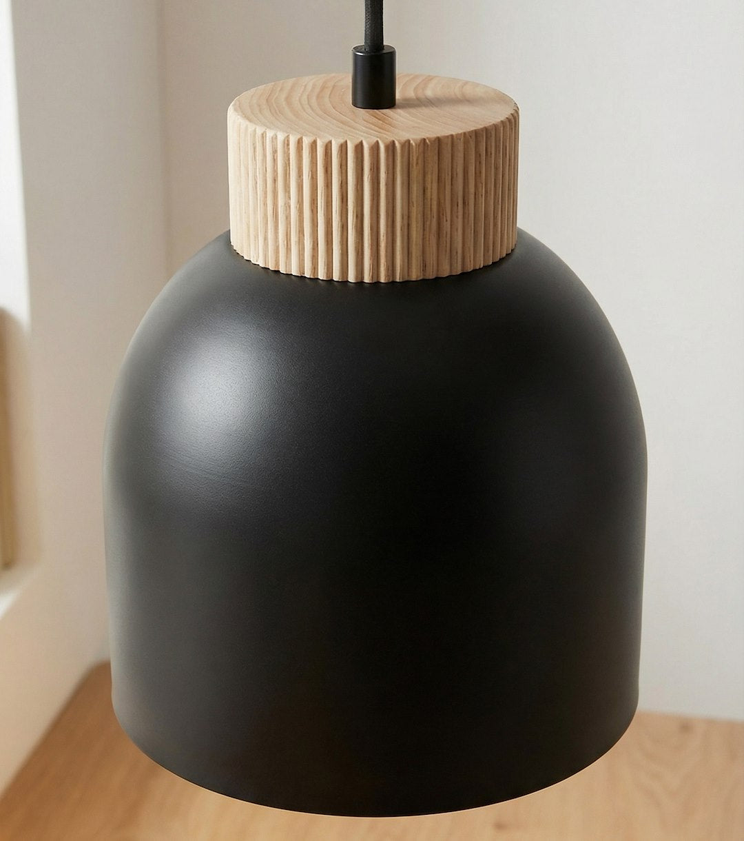 Gros plan sur un abat-jour noir et sa bague en bois cannelé