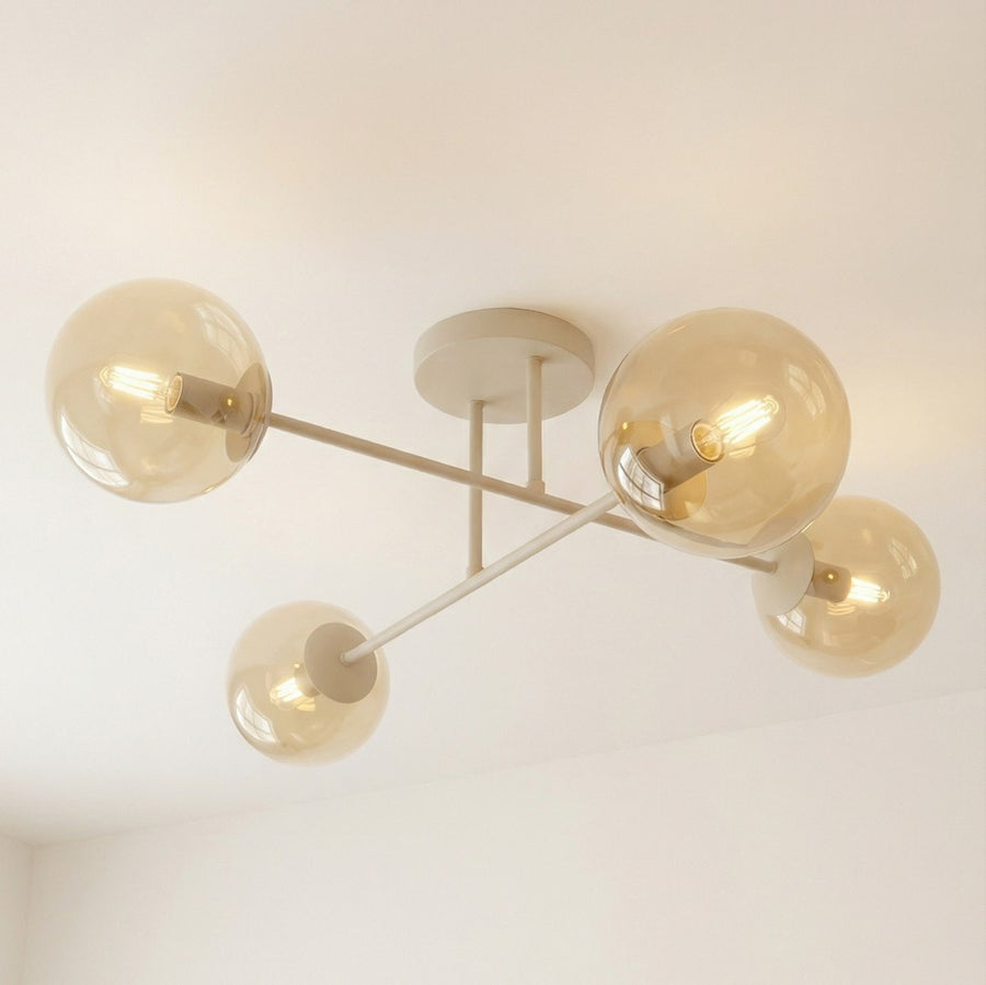 Vue rapprochée : globes ambrés suspendus aux bras croisés en métal beige