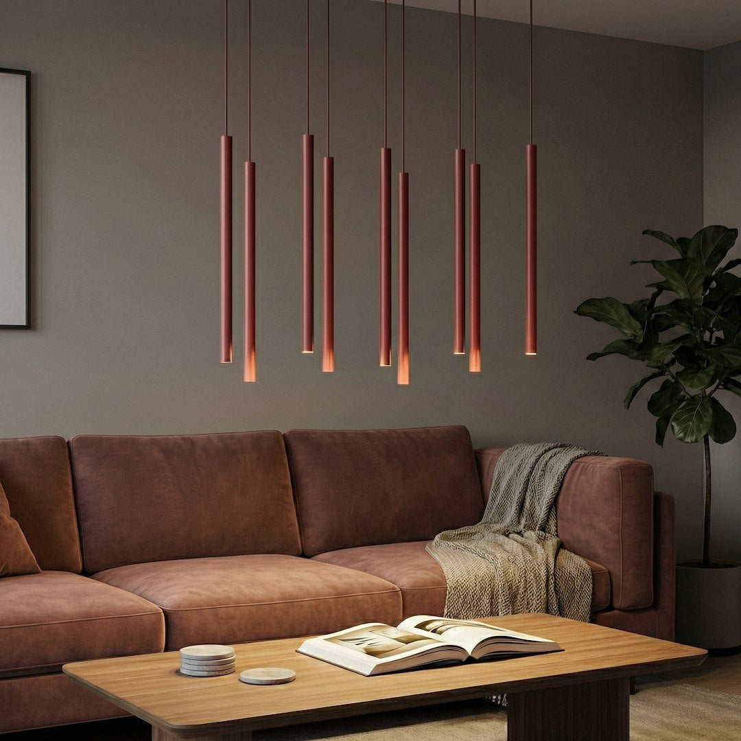 Mise en ambiance salon, canapé en cuir marron, tubes rouges éclairés au-dessus d'une table basse.