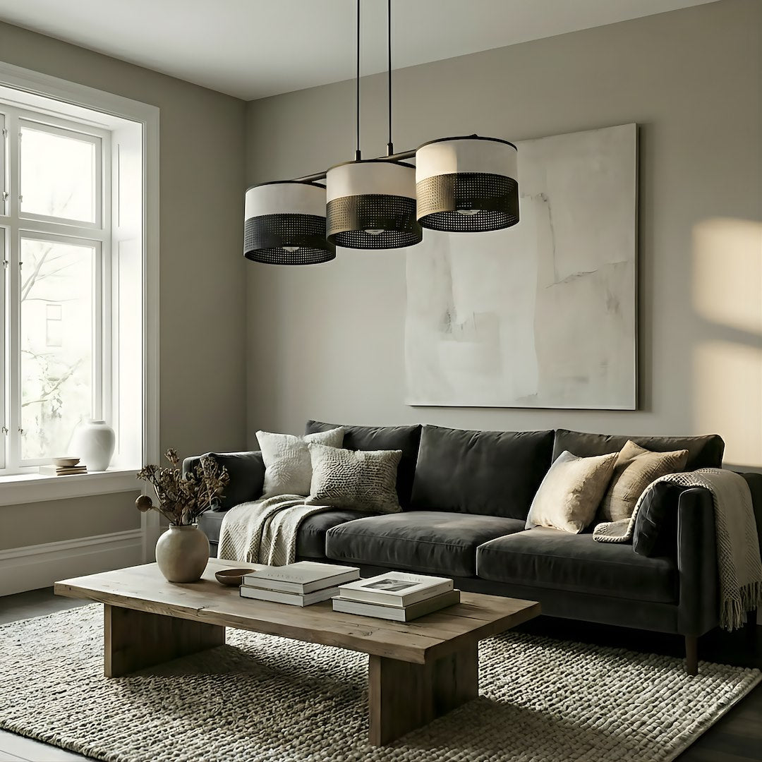Mise en ambiance salon avec suspension allumée au-dessus d'un canapé gris anthracite.