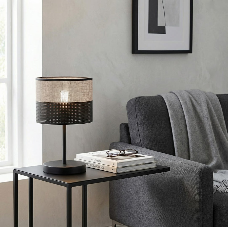 Lampe allumée sur une table d'appoint noire près d'un canapé gris