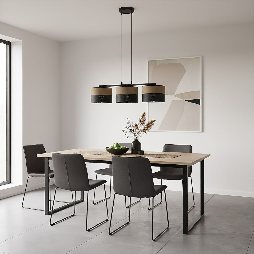 Pièce à vivre claire avec table en bois clair, chaises noires et luminaire à trois cylindres