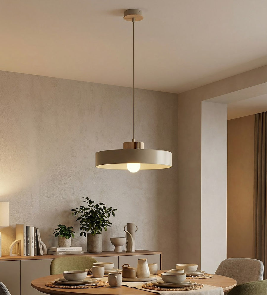 Mise en ambiance dans une salle à manger, suspension allumée au-dessus d'une table dressée.