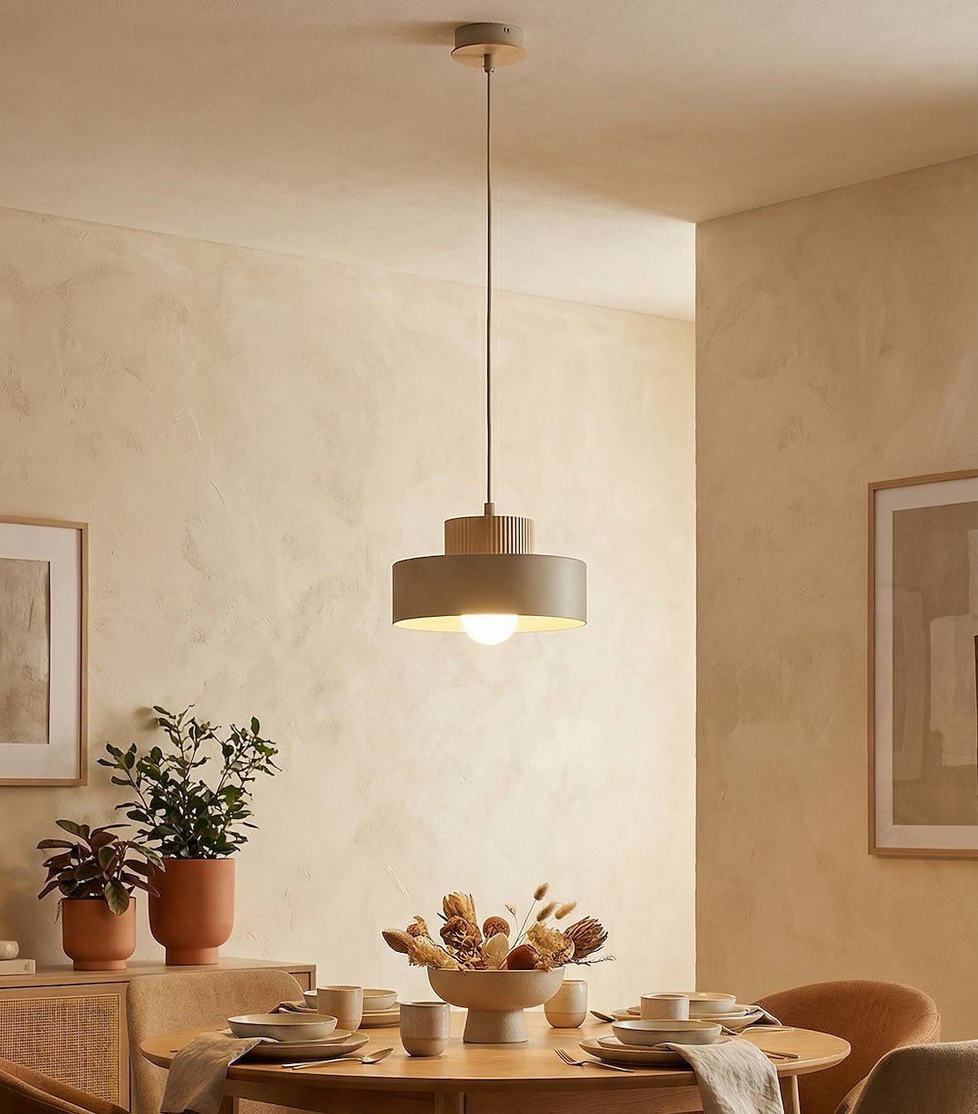 Suspension allumée au-dessus d'une table ronde dressée dans une salle à manger chaleureuse