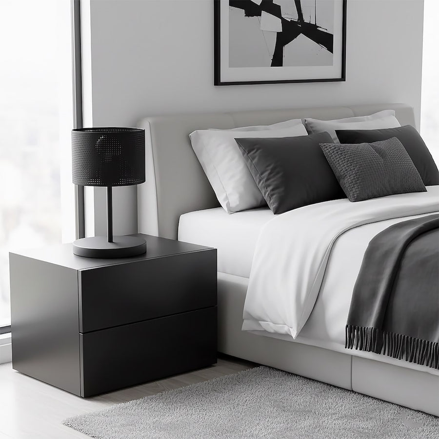Lampe de chevet noire sur meuble noir dans une chambre grise et blanche.