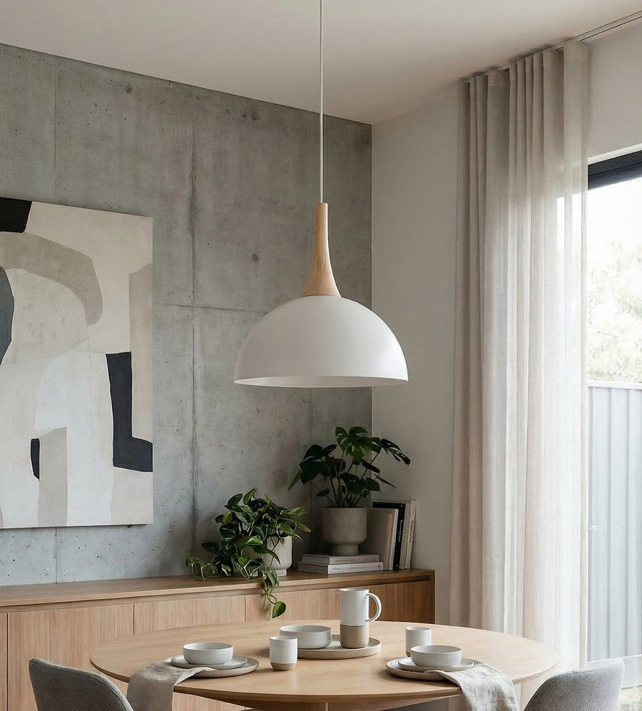Ambiance intérieure : suspension blanche et bois au-dessus d'une table ronde en bois clair.