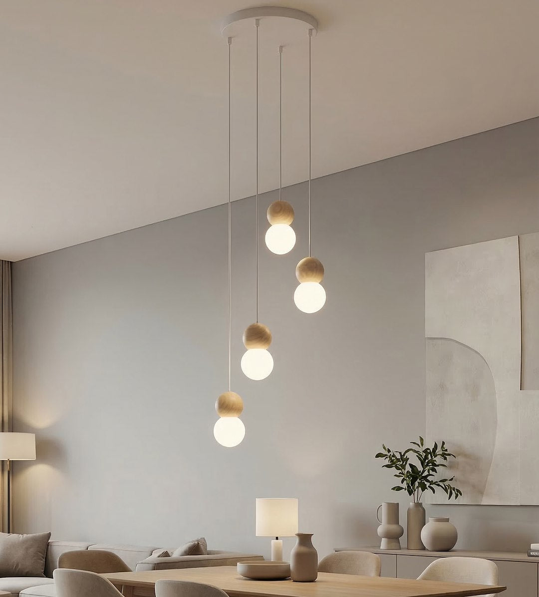 Suspension allumée dans un salon clair, canapé beige et grande toile abstraite