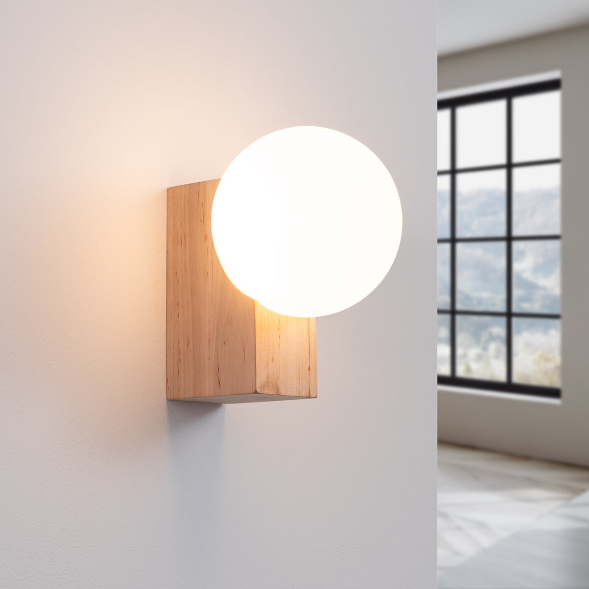 Même applique allumée, diffusant une lumière chaude sur le mur blanc de la pièce.