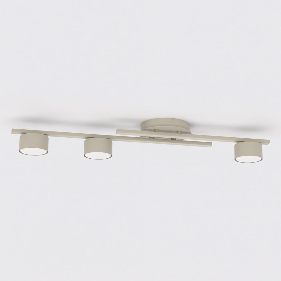 Vue de face du luminaire beige, trois têtes rondes alignées sous la barre centrale