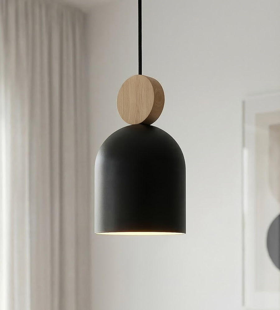 Gros plan sur l'abat-jour noir, le disque en bois et la lumière chaude.