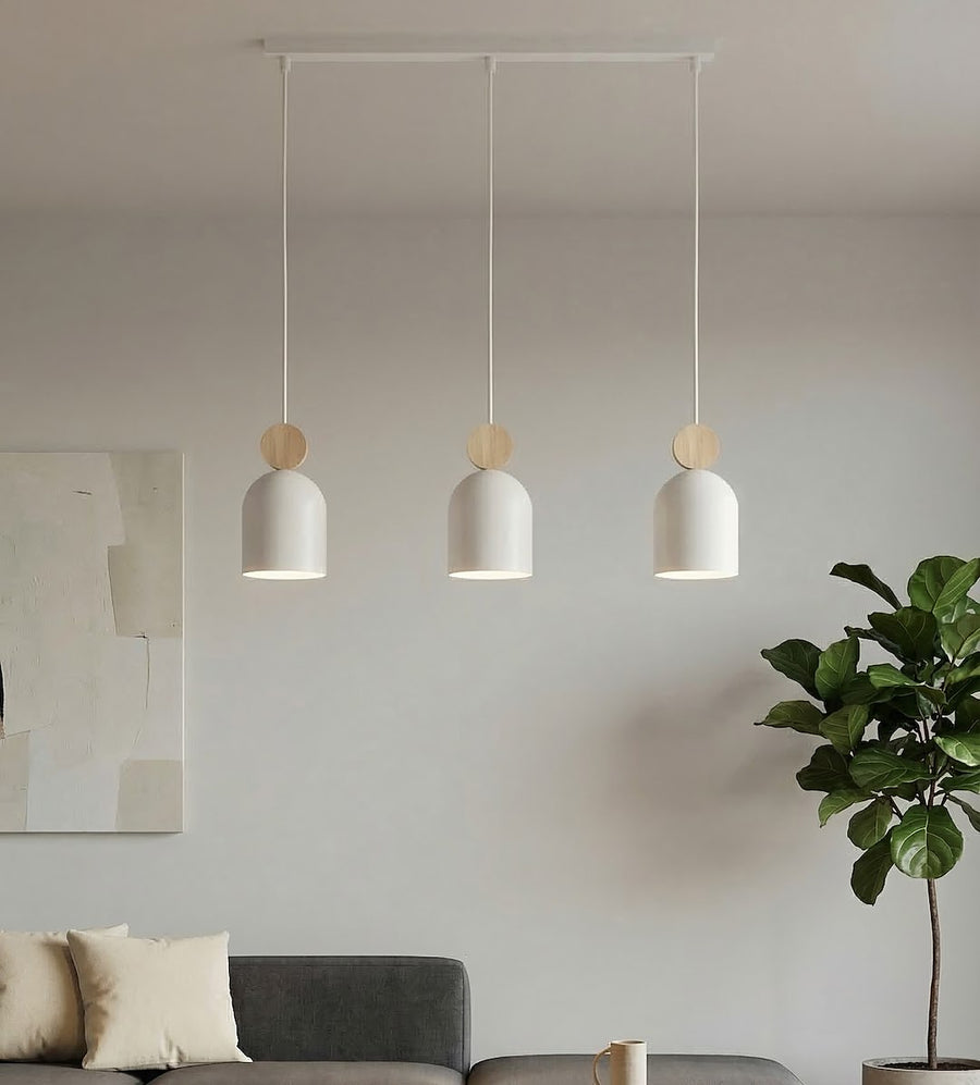 Mise en scène salon avec suspension trois lumières au-dessus d'un canapé gris et plante