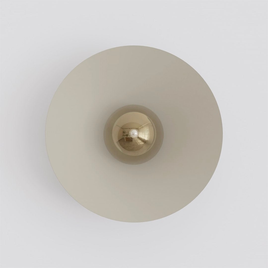 Vue de face de l’applique murale, abat-jour rond beige et ampoule centrale.
