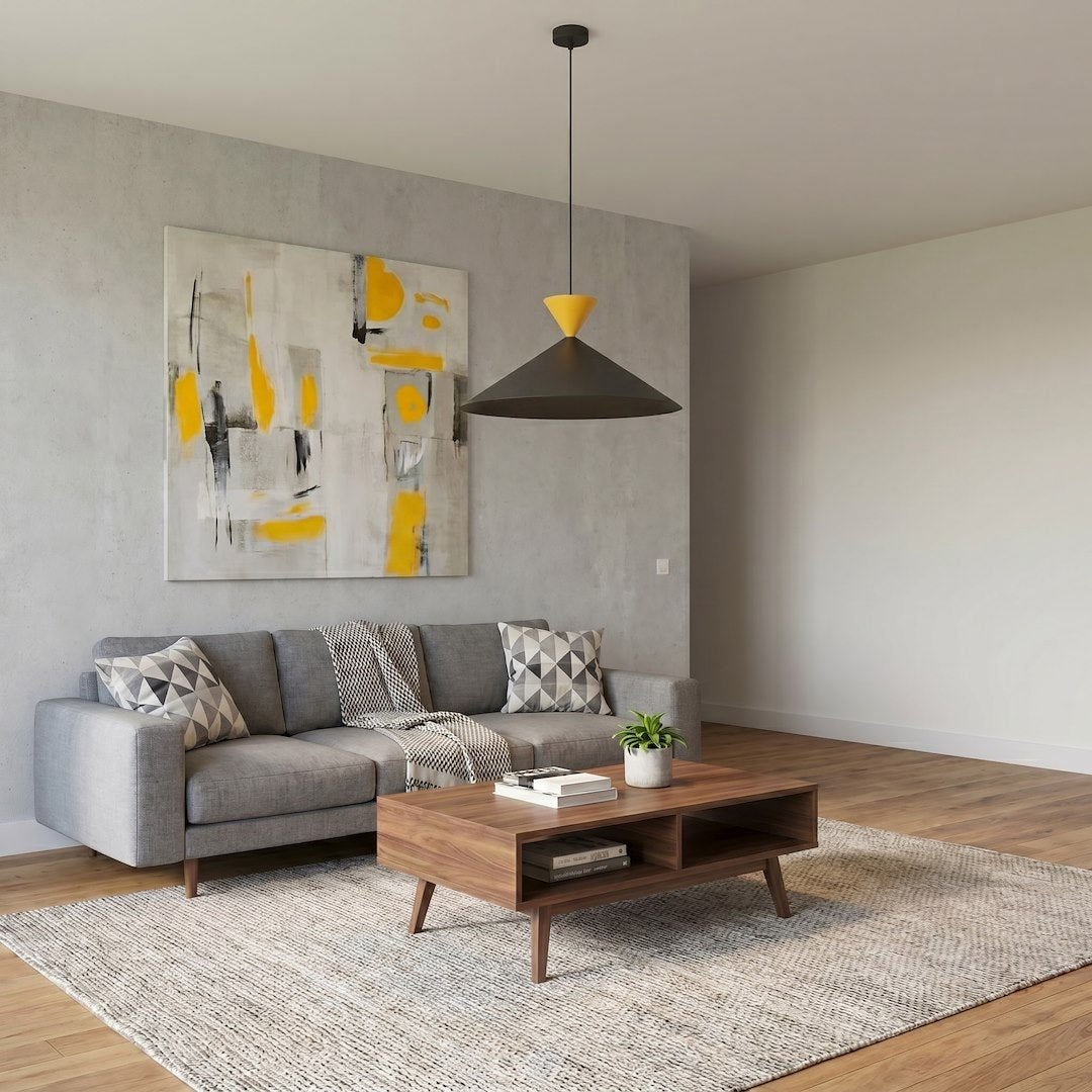 Ambiance salon avec canapé gris et tableau jaune, le luminaire bicolore éclairant la pièce.
