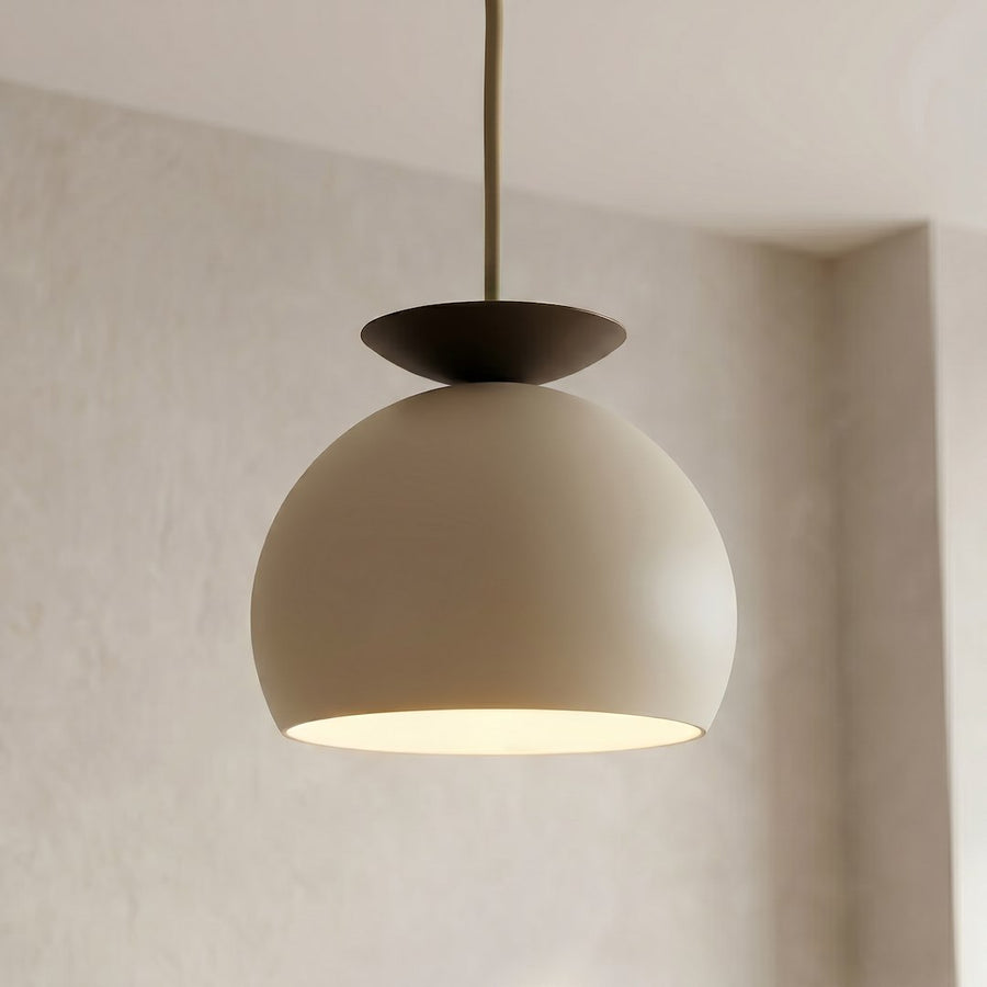 Gros plan sur l'abat-jour bombé beige et le disque supérieur noir de la suspension.