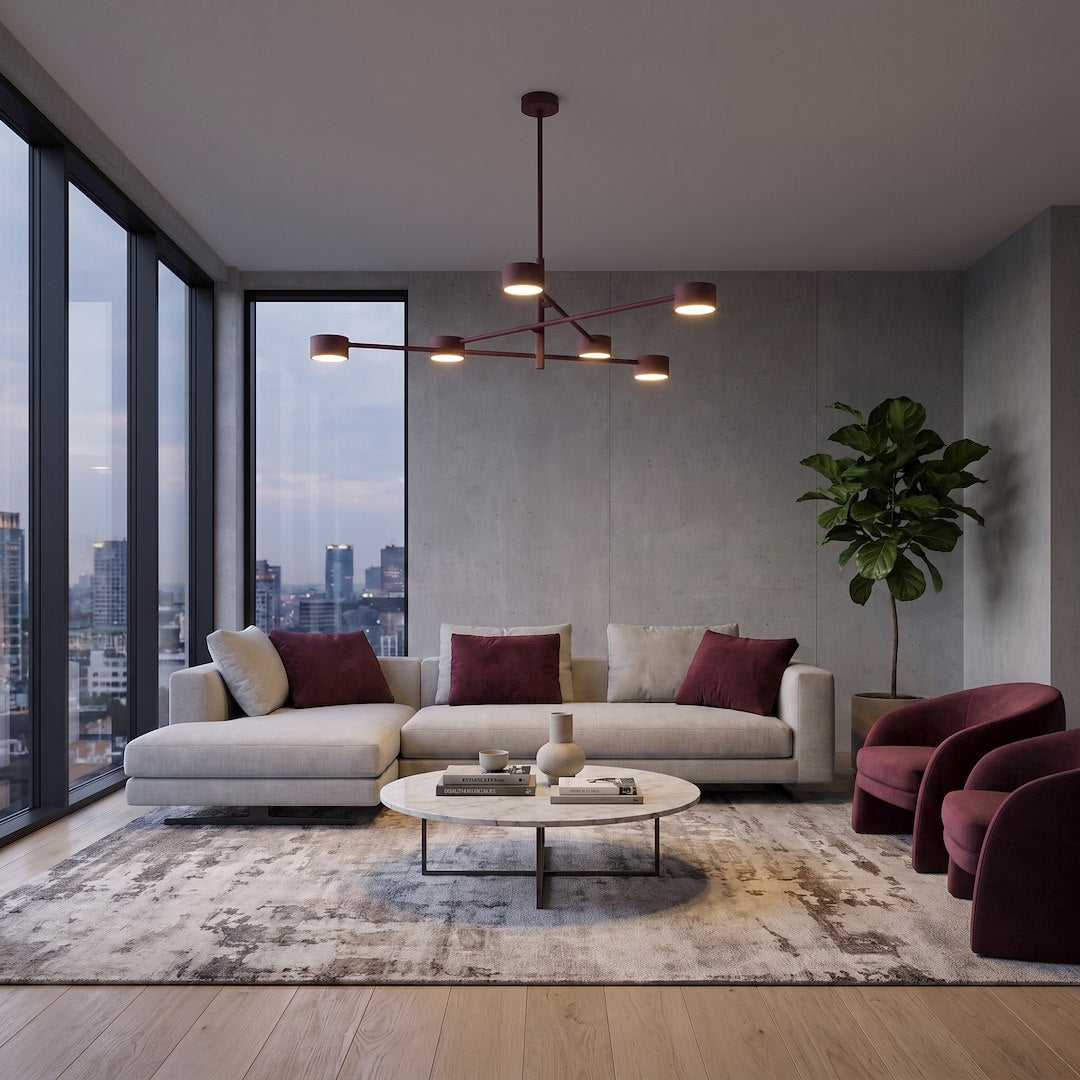 Mise en ambiance salon contemporain, plafonnier bordeaux suspendu au-dessus canapé beige et fauteuils
