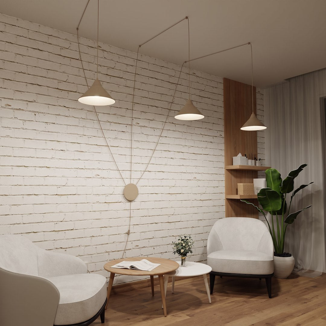 Intérieur au mur de briques blanches, trois suspensions coniques éclairant un coin salon.