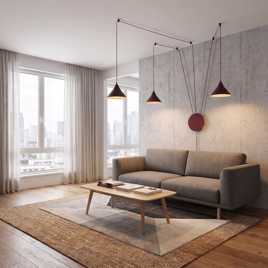 Ambiance intérieure béton et canapé gris sous les trois suspensions rouges