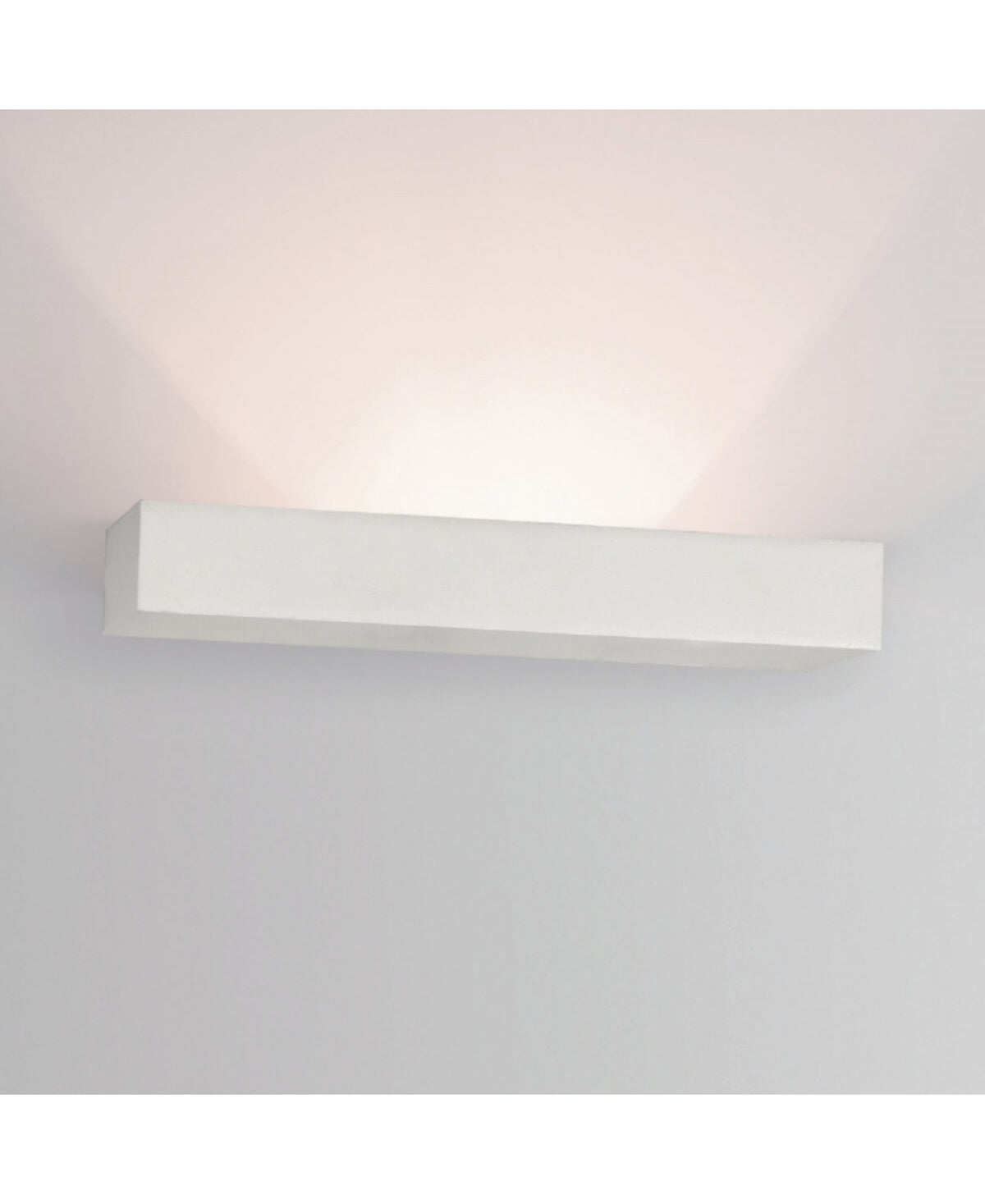 Mise en ambiance de l'applique allumée sur un mur gris clair, halo lumineux
