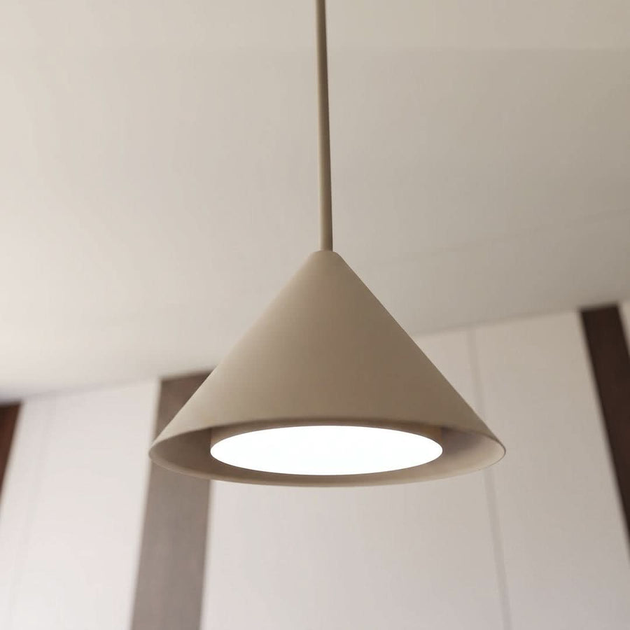 Gros plan sur un abat-jour conique beige éclairé, câble fin et plafond clair