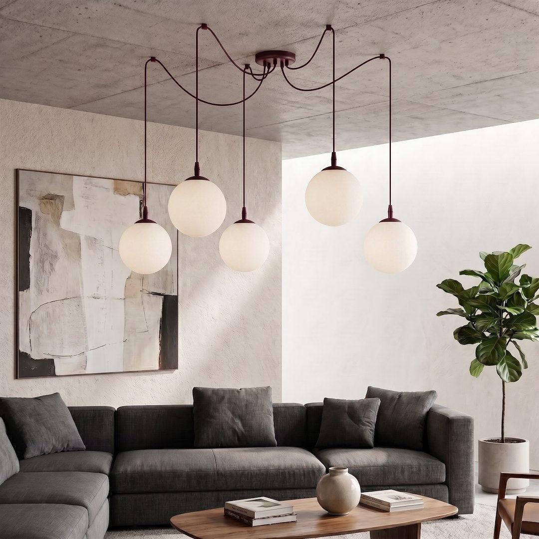 Mise en ambiance salon contemporain, canapé gris et suspension aux cinq globes lumineux suspendus.