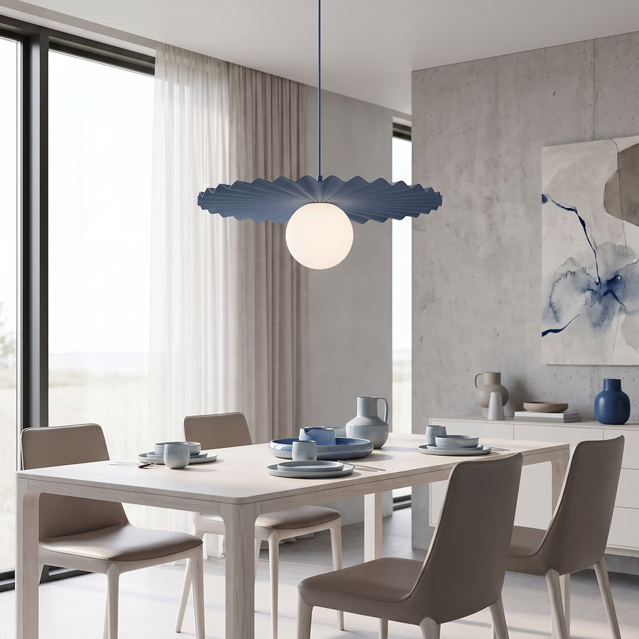 Suspension bleue allumée au-dessus d'une table en bois avec vaisselle bleue.